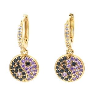 Golden Tai Chi earrings with purple and black cubic zirconia stones on white background