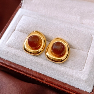 Detail of vintage resin stud earrings in golden metal with red-brown center on velvet