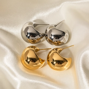 Polished 18k gold and silver thick C-shape hoop earrings on white silk fabric background