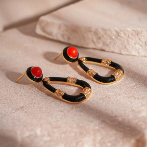Macro shot of vintage U-shaped earrings with black enamel, red stone and gold zircon inlay