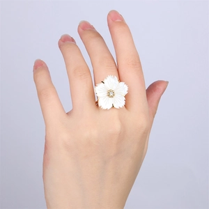 Macro detail of 18k gold plated ring featuring white shell flower and sparkling center zircon