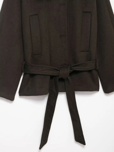 Detail der dunkelbraunen Wolljacke mit Bindegürtel und symmetrischen Taschen am Bund