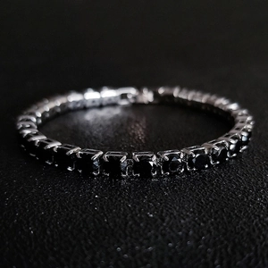 Close-up of black zircon tennis bracelet with silver-tone four-claw settings on leather