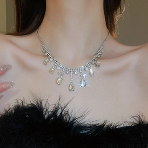 Macro shot of silver-tone tassel necklace with square crystals worn by a model