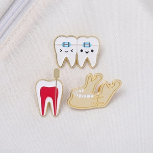 Cartoon tooth enamel pin set with dental motifs and gold metal edges on white fabric