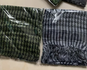 Detail view of military green and grey shemagh scarves with fringes in packaging