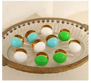 Detail of vintage French style dome earrings in white, mint, and green enamel on gold base