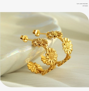 Detailed view of matte gold daisy C-shaped earrings with intricate floral petal textures