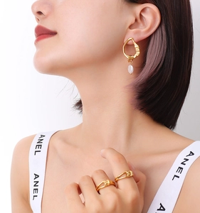 Detail showing asymmetric gold wave earrings with pearls and twisted metal open rings