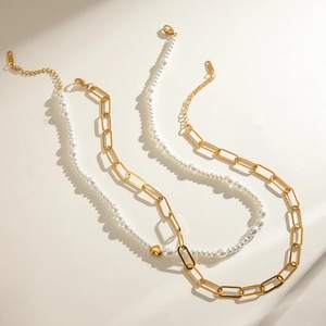 Double-layered gold chain and glass pearl necklace featuring heart charms on white background