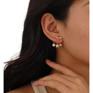 Luxury gold bee earrings with pearls and stars shown on a model side profile