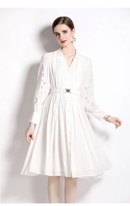 Détails de broderie ajourée sur manches de robe blanche et ceinture à boucle argent