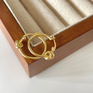 Elegant gold S925 sterling silver knotted hoop earrings displayed on a dark wooden box