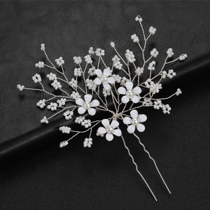 Bridal flower hair pin with white pearls and beads on a textured black background