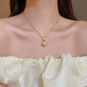 Gros plan d'un collier élégant plaqué or 18K avec une grande perle champagne sur mannequin