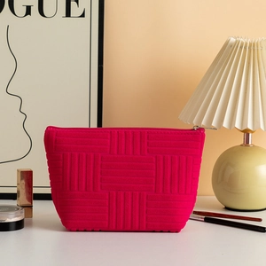 Detail of rose red makeup bag with geometric texture, metal zipper and soft fabric