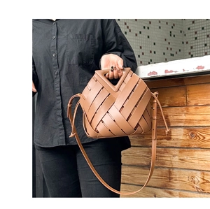 Detail of genuine leather woven handbag featuring a distinctive triangular top handle design