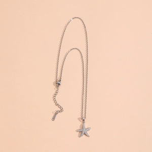 Silver starfish pendant necklace with zircon inlay on a soft pink background