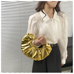 Modische goldene Falten-Handtasche mit Metallic-Finish getragen von einem Model