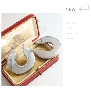 Macro detail of silver U-shaped titanium steel earrings in a vintage red velvet jewelry box