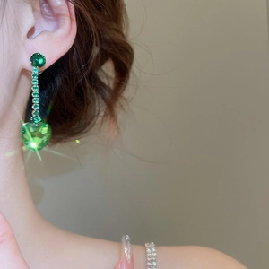 Close-up of green zircon heart tassel earrings on model showing elegant light luxury style