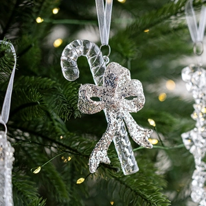 Sparkling silver glitter candy cane ornament with bow hanging on a lush Christmas tree branch