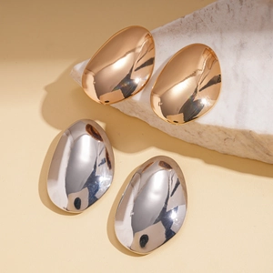 Polished gold and silver sunflower pebble stud earrings on aesthetic white stone display