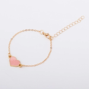 Dettaglio del ciondolo a cuore rosa su bracciale a catena dorata regolabile con chiusura