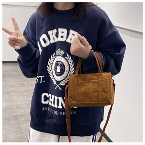 Brown corduroy Boston mini bag worn as a crossbody by a model in a casual outfit