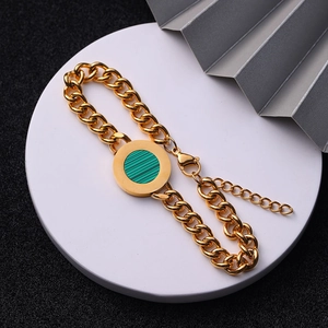 Detail of gold curb chain bracelet featuring a round green striped agate-style charm