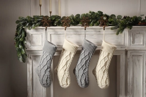 Close-up of knit Christmas stockings in grey and ivory hanging on a festive mantel
