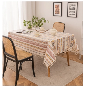 Detail of bohemian linen tablecloth with orange geometric patterns and tassel edges