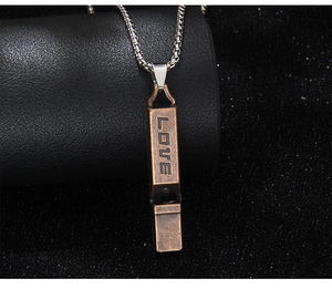Detailed close-up of a bronze vintage whistle pendant engraved with LOVE on a metal chain
