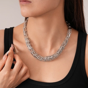 Primo piano di una collana a catena geometrica argentata intrecciata sul collo di una modella