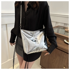 Detail of silver metallic crossbody bucket bag with chain strap and shiny texture finish