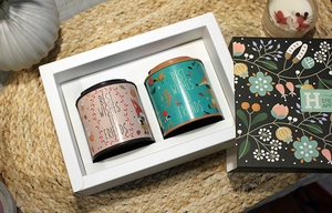Close-up of dual round tin cans with floral fox patterns in a gift box packaging