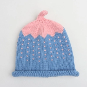 Detailed knit texture of pink and blue baby beanie with heart jacquard pattern