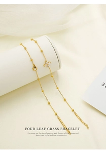 Detail of gold four-leaf clover bracelet with sparkling zircons on white display