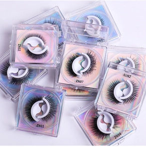 Close-up of assorted natural false eyelashes in transparent boxes with holographic cards
