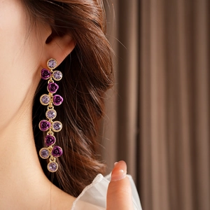 Vue détaillée de longues boucles d'oreilles roses mauves à pampilles sur un mannequin