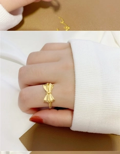 Close-up of elegant matte gold bow ring with wheat ear detail on model hand