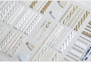 Macro detail of 3D embossed nail art stickers with knit sweater textures and cable patterns
