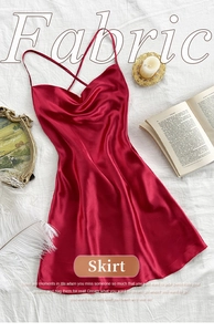 Detail of red satin nightgown with cross-back straps and draped neckline on white fabric