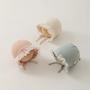 Dettaglio cappellini neonato in cotone con pizzo e ricami floreali fatti a mano