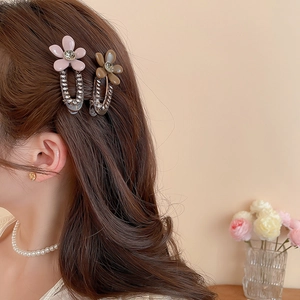 Detailed view of rhinestone-encrusted acrylic flower hair clips worn by a model