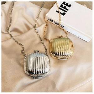 Close-up of vertical striped metal chain bags in gold and silver on silk fabric