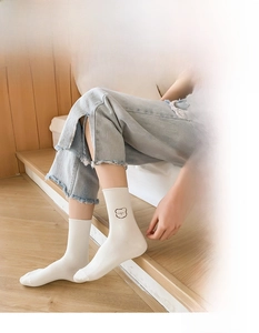 Detail of white cotton crew socks with dark bear embroidery and ribbed cuffs