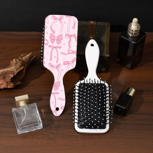 Dettaglio della spazzola per capelli rosa con fiocco e pettine su tavolo di legno