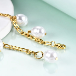 18K gold plated Figaro chain bracelet with 12mm pearls and lobster clasp on light green background