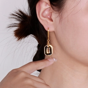 Detail of gold drop earrings with black geometric pendant and a sparkling white zircon